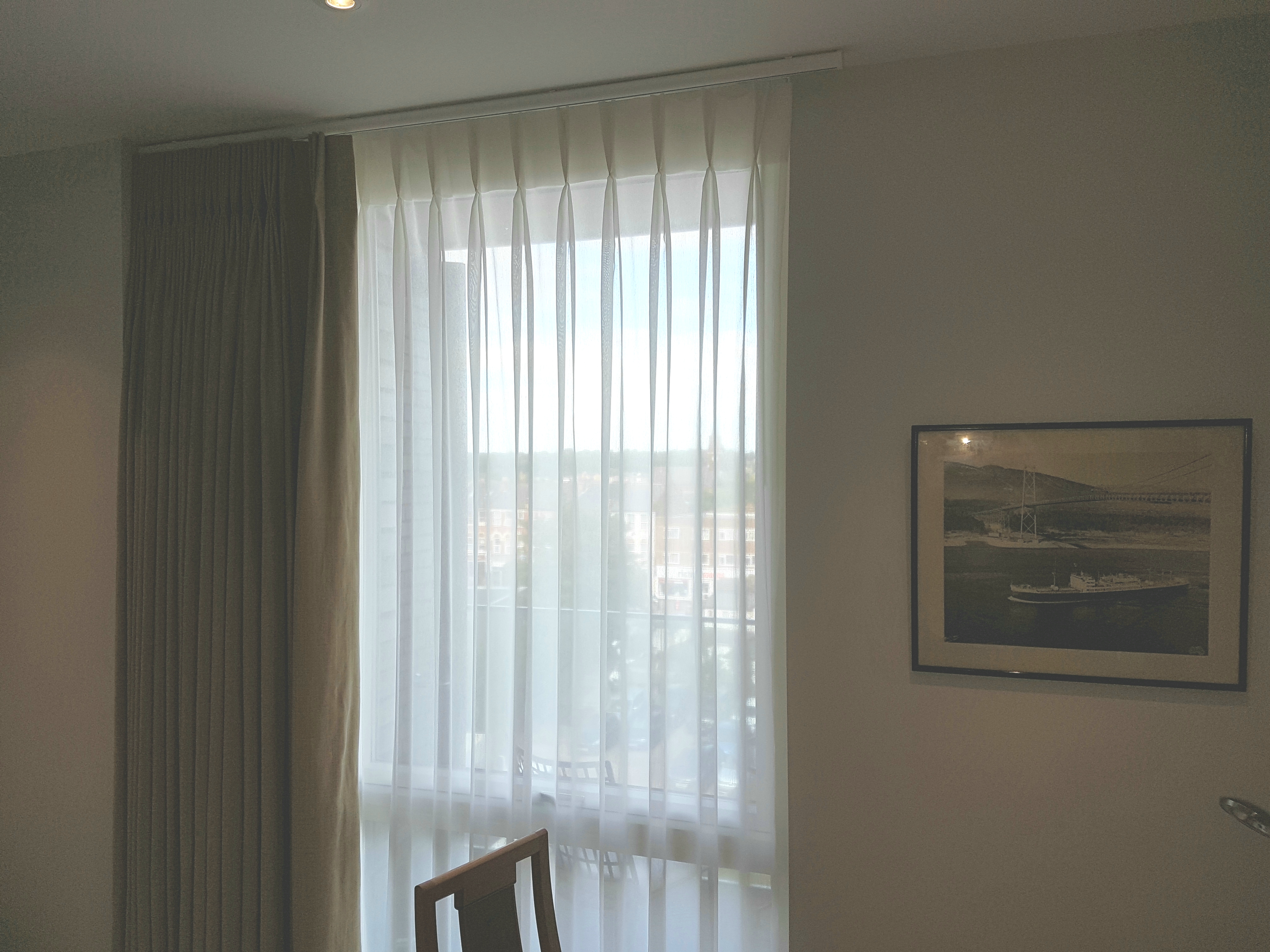 Single double pleat sheer curtain and blackout curtain installed to a curtain track and a pole